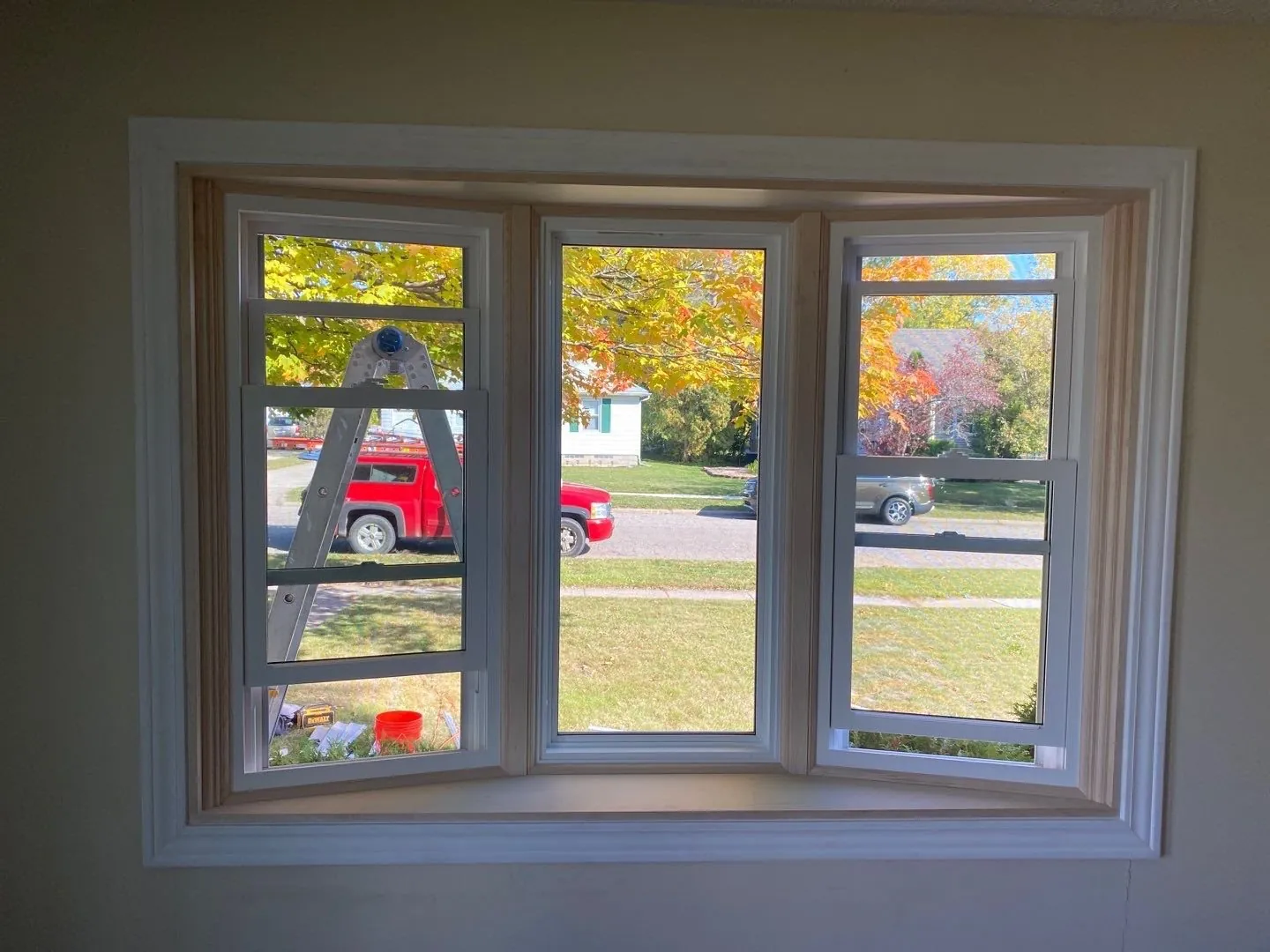 Newly installed white vinyl bay windows on a blue-sided Greater Lansing home